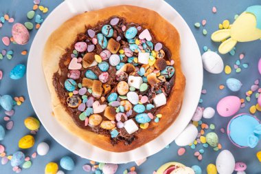 Tatlı Paskalya tatlı pizzası, çikolata soslu, marşmelov ve çikolatalı yumurta, Paskalya bayramı çocukları için atıştırmalık, şenlikli süslemeler, renkli yumurtalar ve tavşan tavşanlı.