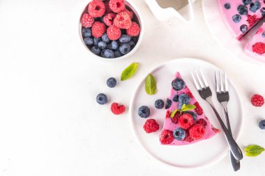 Yaz meyveli ve fırınlanmamış peynirli kek. Kremalı pasta ve çikolatalı kek, pembe peynir tabakası, yabanmersini, ahududu, çilek, nane yaprağı, beyaz masa fotokopisi alanı.