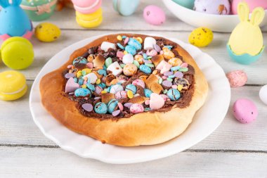 Tatlı Paskalya tatlı pizzası, çikolata soslu, marşmelov ve çikolatalı yumurta, Paskalya bayramı çocukları için atıştırmalık, şenlikli süslemeler, renkli yumurtalar ve tavşan tavşanlı.
