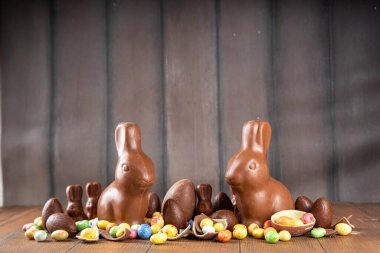 Paskalya arkaplan tebrik kartı, geleneksel şekerleme, Paskalya yumurtası avı eğlence konsepti. Çikolata tavşanı, çikolata ve şeker Tahta arka planda Paskalya yumurtası