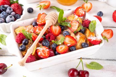 Yaz meyvesi ve Fransız tostu fırınlanmış güveç. Ev yapımı lezzetli Fransız tostu, kremalı kahvaltı pastası, kızarmış ekmek ve taze çilek, yabanmersini, ahududu ve kirazlı.