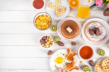 Paskalya tatili tatlı kahvaltı, brunch. Paskalya süslü Belçika waffle 'ları, krepler, kahvaltı gevrekleri ve süt, kızarmış yumurtalar kızarmış ekmek ve pastırma, Paskalya çikolatalı yumurtalar ve bahar çiçekleriyle birlikte tavşan.