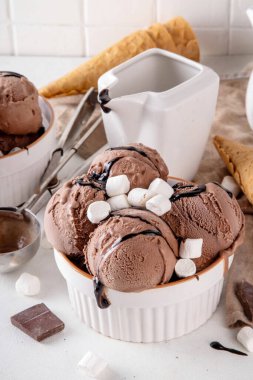 Koyu çikolata soslu sıcak çikolata dondurması ve lokum. Beyaz kasede çikolatalı dondurma, üzerine çikolata serpiştirilmiş beyaz mutfak masasında fotokopi alanı.