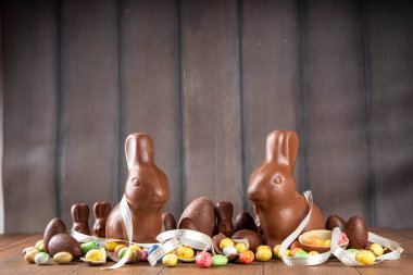 Paskalya arkaplan tebrik kartı, geleneksel şekerleme, Paskalya yumurtası avı eğlence konsepti. Çikolata tavşanı, çikolata ve şeker Tahta arka planda Paskalya yumurtası