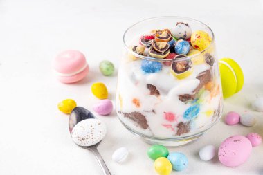 Paskalya yumurtalı browni peynirli parfe bardakta, çikolatalı yumurta, bisküvi, vanilyalı krema ve şeker dekoru ile katmanlı tatlı tatlı kahvaltılık yoğurt.