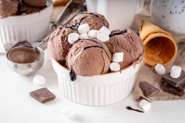 Koyu çikolata soslu sıcak çikolata dondurması ve lokum. Beyaz kasede çikolatalı dondurma, üzerine çikolata serpiştirilmiş beyaz mutfak masasında fotokopi alanı.
