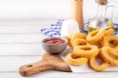 Ketçap soslu altın soğan halkaları, uçak fritözü beyaz ahşap masa fotokopi alanında lezzetli soğan halkaları atıştırmalıkları.