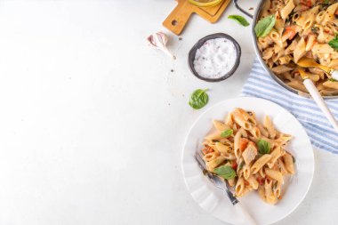 Son moda viral benimle tavuk makarnası evlen. Bir tencere yumuşak makarna ve kremalı ve peynirli sulu tavuk parçaları, sarımsaklı güneşte kurutulmuş domates sosu, nükteli fesleğen yaprağı, tabak ve demlikte.