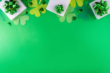 Shamrock Aziz Patrick 'in günü parlak renkli arka plan, parti kutuları, dekorları, yoncaları ve yeşil arka planda altın sikkeleri olan Aziz Patrick bayramı düzlüğü.