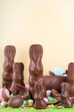 Paskalya yumurtası avı, satış ve tatil gelenekleri. Çeşitli şeker ve çikolatalı Paskalya yumurtaları, parlak yeşil arka planda tavşan ve tavşanlar. Paskalya hazırlığı, tebrik kartı, Paskalya indirimi ve alışveriş