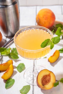 Şeftalili martini ya da margarita ya da limonata soğuk meyve suyu, nane ve limonlu yaz meyve suyu kokteyli, beyaz ahşap masa.