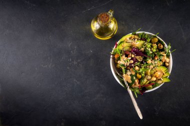 Bitki temelli keto yiyecekler, düşük karbonhidratlı vegan salatası çeşitli yeşil sebzeler, avokado, roka, ıspanak, marul, beyaz peynir, fındık, fıstık, fıstık ezmesi, avokado ve zeytin.