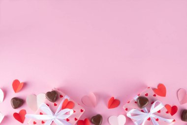 Sevgililer Günü için güzel pembe bir arkaplan. Sevgililer Günü tebrik kartı düzlüğü, hediye kutusu, kurdeleler, çikolatalar ve kalp dekorasyonu ile yatıyordu.
