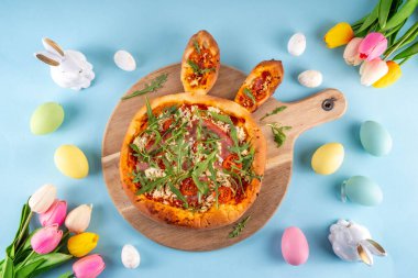 Yaratıcı, tavşan kulaklı Paskalya Tavşanı şekilli pizza yaptı. Domatesli Paskalya bayramı pizzası, pastırma ve taze roka, dekorlu - tavşanlar, Paskalya yumurtaları kopyalama alanı