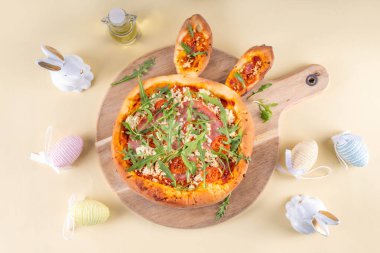 Yaratıcı, tavşan kulaklı Paskalya Tavşanı şekilli pizza yaptı. Domatesli Paskalya bayramı pizzası, pastırma ve taze roka, dekorlu - tavşanlar, Paskalya yumurtaları kopyalama alanı