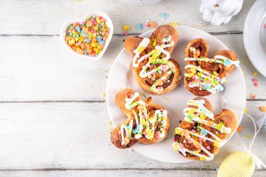 Tatlı ve lezzetli Paskalya tavşanı tarçınlı çörekler. Tatlı tavşan şekilli çörekler, renkli paskalya şekeri parçacıkları, paskalya süslemeleri, renkli yumurtalar ve tavşan tavşanları, kopya alanı