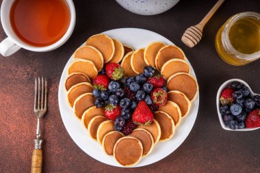 Sevgililer Günü tatlı kahvaltı krepleri kalp şeklinde serilmiş, taze ahududu, yabanmersini ve bal ile çay fincanı ve çaydanlık ile, kopyalama alanı ile