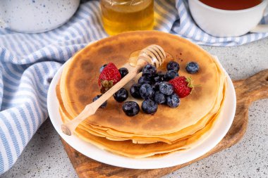 Ev yapımı küçük Fransız krepleri, böğürtlen ve ballı tereyağlı kekler. Bir yığın taze pişmiş geleneksel Maslenitsa yemeği, Doğu Avrupa Slav ince krep kahvaltısı ya da öğle yemeği