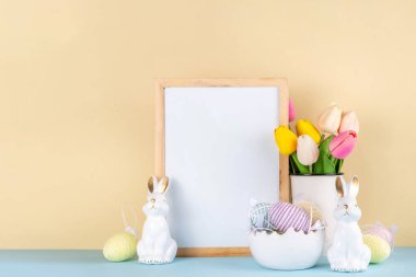 Bahar Paskalya bayramı masası boyalı Paskalya yumurtaları, bahar çiçekleri buketi, dekoratif tavşanlar, beyaz mutfak arka planında