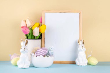 Bahar Paskalya bayramı masası boyalı Paskalya yumurtaları, bahar çiçekleri buketi, dekoratif tavşanlar, beyaz mutfak arka planında