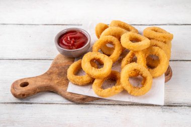 Ketçap soslu altın soğan halkaları, uçak fritözü beyaz ahşap masa fotokopi alanında lezzetli soğan halkaları atıştırmalıkları.