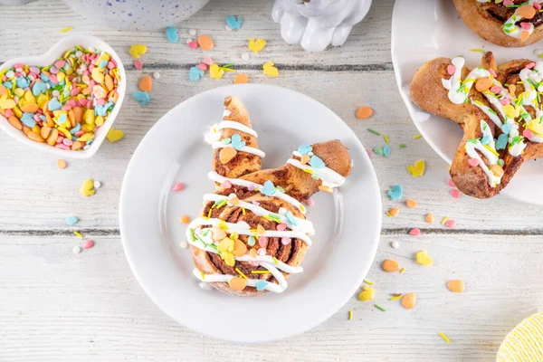 Tatlı ve lezzetli Paskalya tavşanı tarçınlı çörekler. Tatlı tavşan şekilli çörekler, renkli paskalya şekeri parçacıkları, paskalya süslemeleri, renkli yumurtalar ve tavşan tavşanları, kopya alanı