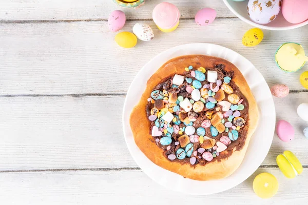 Tatlı Paskalya tatlı pizzası, çikolata soslu, marşmelov ve çikolatalı yumurta, Paskalya bayramı çocukları için atıştırmalık, şenlikli süslemeler, renkli yumurtalar ve tavşan tavşanlı.