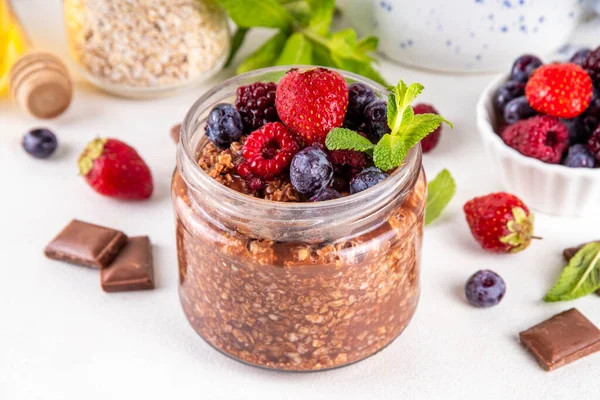 Çikolatalı Yulaf ezmesi, çikolata soslu, fındıklı ve taze dutlu, beyaz mutfak masasında yuvarlanmış yulaf, ahududu, yaban mersini, çilekli