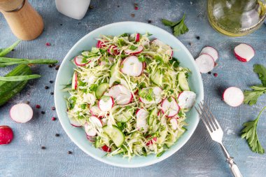 Salatalık ve turplu lahana salatası. Genç bahar sebzelerinin sağlıklı diyet vitamin salatası: lahana, turp, salatalık, taze otlar ve zeytinyağı