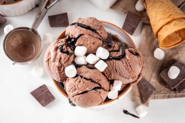 Koyu çikolata soslu sıcak çikolata dondurması ve lokum. Beyaz kasede çikolatalı dondurma, üzerine çikolata serpiştirilmiş beyaz mutfak masasında fotokopi alanı.