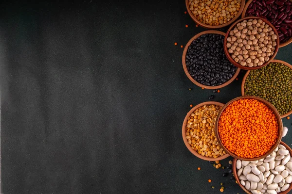 Çeşitli kuru fasulyeler, mercimek, mung, nohut, ahşap kaselerde bezelye çeşitleri. Legumes beyaz masa üst görünümünde. Vegan protein kaynakları yiyecek, kopyalama alanı