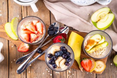 Çilekli, yeşil elmalı, böğürtlenli ve muzlu tatlı yulaf. Üç bardak dengeli yulaf ezmesi yoğurt, meyve ve böğürtlen. Diyet sağlıklı yaz atıştırması ya da kahvaltı