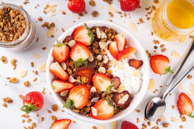 Sağlıklı yaz meyveli kahvaltı kasesi granola, kremalı Yunan yoğurdu ve çilekli. Lezzetli dengeli atıştırmalık, kilo kaybı, sağlıklı sabah yemeği tarifi.