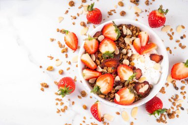 Sağlıklı yaz meyveli kahvaltı kasesi granola, kremalı Yunan yoğurdu ve çilekli. Lezzetli dengeli atıştırmalık, kilo kaybı, sağlıklı sabah yemeği tarifi.