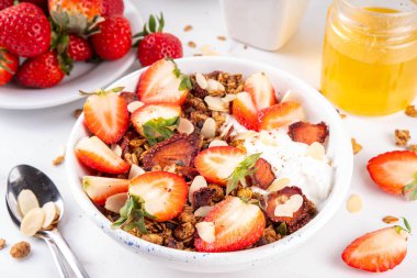 Sağlıklı yaz meyveli kahvaltı kasesi granola, kremalı Yunan yoğurdu ve çilekli. Lezzetli dengeli atıştırmalık, kilo kaybı, sağlıklı sabah yemeği tarifi.