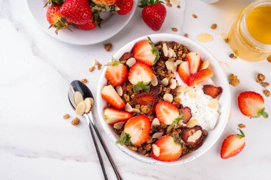 Sağlıklı yaz meyveli kahvaltı kasesi granola, kremalı Yunan yoğurdu ve çilekli. Lezzetli dengeli atıştırmalık, kilo kaybı, sağlıklı sabah yemeği tarifi.