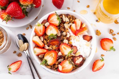Sağlıklı yaz meyveli kahvaltı kasesi granola, kremalı Yunan yoğurdu ve çilekli. Lezzetli dengeli atıştırmalık, kilo kaybı, sağlıklı sabah yemeği tarifi.