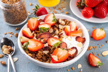 Sağlıklı yaz meyveli kahvaltı kasesi granola, kremalı Yunan yoğurdu ve çilekli. Lezzetli dengeli atıştırmalık, kilo kaybı, sağlıklı sabah yemeği tarifi.