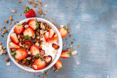 Sağlıklı yaz meyveli kahvaltı kasesi granola, kremalı Yunan yoğurdu ve çilekli. Lezzetli dengeli atıştırmalık, kilo kaybı, sağlıklı sabah yemeği tarifi.