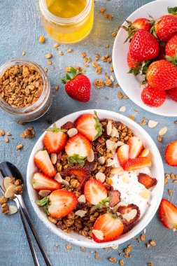 Sağlıklı yaz meyveli kahvaltı kasesi granola, kremalı Yunan yoğurdu ve çilekli. Lezzetli dengeli atıştırmalık, kilo kaybı, sağlıklı sabah yemeği tarifi.