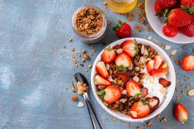 Sağlıklı yaz meyveli kahvaltı kasesi granola, kremalı Yunan yoğurdu ve çilekli. Lezzetli dengeli atıştırmalık, kilo kaybı, sağlıklı sabah yemeği tarifi.