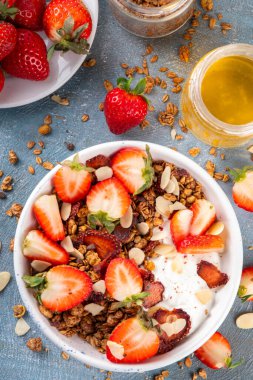 Sağlıklı yaz meyveli kahvaltı kasesi granola, kremalı Yunan yoğurdu ve çilekli. Lezzetli dengeli atıştırmalık, kilo kaybı, sağlıklı sabah yemeği tarifi.