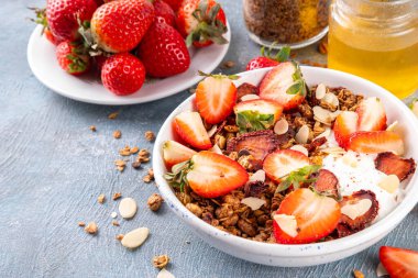 Sağlıklı yaz meyveli kahvaltı kasesi granola, kremalı Yunan yoğurdu ve çilekli. Lezzetli dengeli atıştırmalık, kilo kaybı, sağlıklı sabah yemeği tarifi.