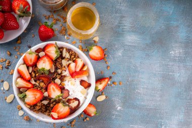 Sağlıklı yaz meyveli kahvaltı kasesi granola, kremalı Yunan yoğurdu ve çilekli. Lezzetli dengeli atıştırmalık, kilo kaybı, sağlıklı sabah yemeği tarifi.