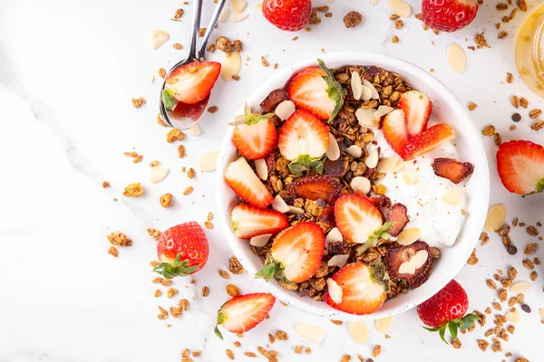 Sağlıklı yaz meyveli kahvaltı kasesi granola, kremalı Yunan yoğurdu ve çilekli. Lezzetli dengeli atıştırmalık, kilo kaybı, sağlıklı sabah yemeği tarifi.