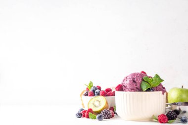 Ev yapımı meyve ve meyveli dondurma, sağlıklı meyve ve yoğurt ile porsiyonlu dondurma taze yaban mersini, ahududu, çilek, böğürtlen, elmalar, mutfak masasında kivi.