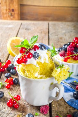 Limonlu kek. Mikrodalgada tatlı yaz tatlısı. Taze böğürtlenli ve çırpılmış kremalı limonlu turtalar ahşap arka planda.
