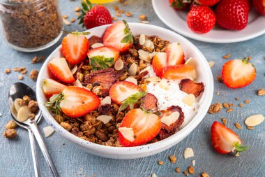 Sağlıklı yaz meyveli kahvaltı kasesi granola, kremalı Yunan yoğurdu ve çilekli. Lezzetli dengeli atıştırmalık, kilo kaybı, sağlıklı sabah yemeği tarifi.
