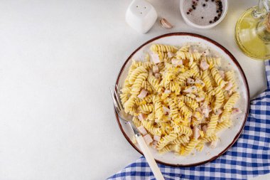 Peynirli kremalı soslu lezzetli fussilli carbonara makarnası, üstüne kurutulmuş otlar ve rendelenmiş peynir.