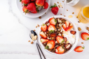 Sağlıklı yaz meyveli kahvaltı kasesi granola, kremalı Yunan yoğurdu ve çilekli. Lezzetli dengeli atıştırmalık, kilo kaybı, sağlıklı sabah yemeği tarifi.